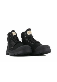 Botas de tobillo negras de lona con suela de goma texturizada, con ojales de metal, parte frontal con cordones y una cremallera lateral para un fácil acceso.