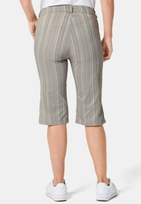 Lichtgrijze capri-broek met dunne verticale strepen, een rechte snit en een gladde textuur, gecombineerd met witte sneakers.