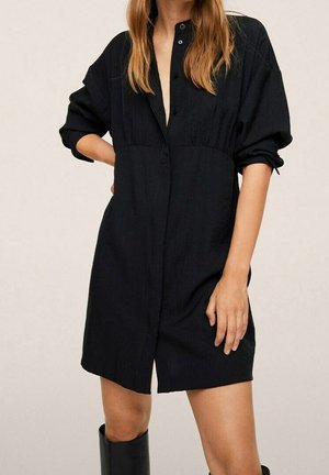 Abito nero con bottoni, dalla vestibilità ampia, maniche corte e cintura in vita. Il tessuto sembra testurizzato, con un design a scollatura a V profonda.
