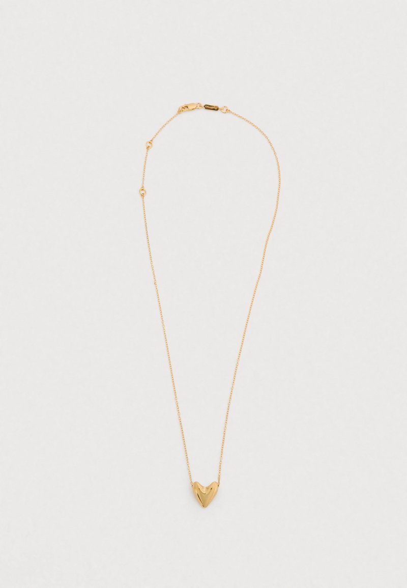 Κολιέ με μενταγιόν σε σχήμα χρυσής καρδιάς σε λεπτή αλυσίδα. Η καρδιά είναι λεία με απαλές καμπύλες, και η αλυσίδα διαθέτει μικρές στρογγυλές λεπτομέρειες.