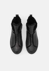 Botas negras de tobillo con un exterior de cuero liso, forro de piel de pelo alrededor del cuello, paneles laterales elásticos y una suela de goma resistente.
