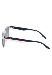 Occhiali da sole trasparenti con aste in acetato blu navy. Presentano una striscia di accento rossa e una superficie testurizzata per una migliore presa sulla parte interna dell'asta. Design leggero.