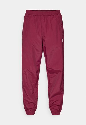 Pantalones de chándal burdeos hechos de material ligero, con una cinturilla elástica, puños en los tobillos y un pequeño detalle del logo en el costado.