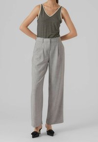 Haut sans manches à rayures noir et crème, pantalon taille haute gris clair, design à jambes larges, texture lisse, accompagné de mules à talons noirs.