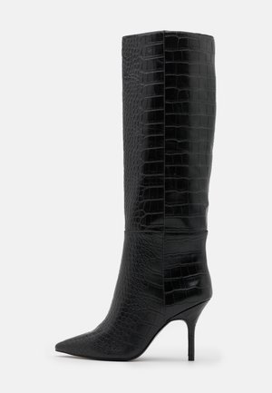 Sort knæhøj støvle med spids tå, høj stiletthæl og krokodilletekstur på en glat læderoverflade.
