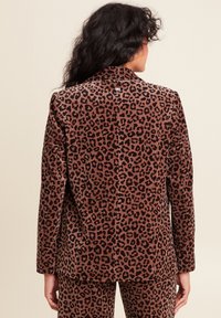 Blazer en velours côtelé marron avec imprimé léopard noir, fente simple à l'arrière, revers crantés et détail de bouton au col.