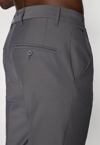 Gray trousers featuring a smooth texture, flat front, and back pocket with a button closure; clean lines and tailored fit.