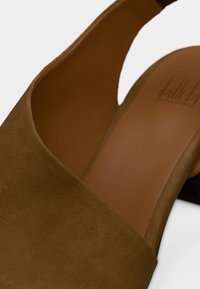 Κοντινό πλάνο ταμπά μπεζ μοκασίνι mule με ανοιχτό δάχτυλο, χοντρό τακούνι και λείο δερμάτινο πάτο.