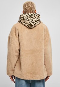 Bežová umelá kožušina oversize bunda s kapucňou s leopardím vzorom. Má voľný strih a mäkkú textúru, vhodná na bežné nosenie.