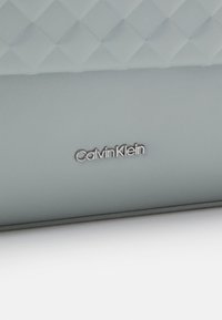 Portafoglio Calvin Klein in materiale testurizzato blu chiaro con un motivo trapuntato, caratterizzato da un dettaglio logo in argento e bordi lisci.