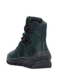 Botte de cheville en cuir vert avec finition texturée, bout rond, accents élastiques sur les côtés et semelle en caoutchouc noire. Présente des détails de couture rouge contrastants.