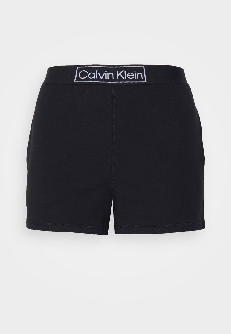 Fekete rövidnadrág puha textúrával és rugalmas derékpánttal, fehér "Calvin Klein" logóval. Egyenes vonalú, varrt szegéllyel.