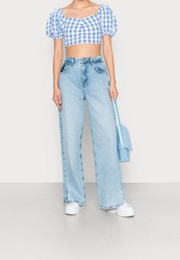 Blå gingham cropped top med puffærmer, parret med lyseblå vide bukser og hvide platform sneakers. Tote taske i lyseblå.
