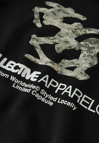 Črna majica iz blaga z vzorcem kamuflaže in belim napisom "COLLECTIVE APPAREL" ter dodatnimi blagovnimi podrobnostmi.