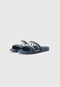 Sandales à glissière bleu marine avec un dessus texturé, arborant un grand logo blanc "REPLAY" et un design discret. Matériau doux et flexible.