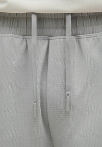 Lichtgrijze, gestructureerde sweatpants met een elastische tailleband, een contrasterend trekkoord en gladde stofaccenten bij de taille.