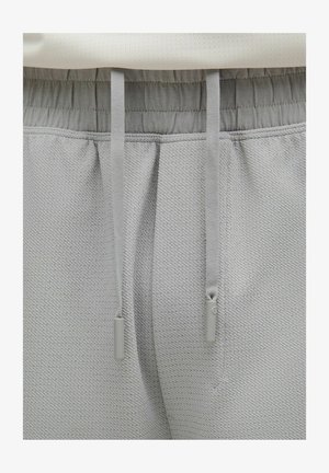 Lys grå teksturerede sweatpants med elastisk talje, kontrasterende snøre og glatte stofdetaljer ved taljen.