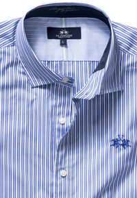 Ljusbl å och vitrandig skjorta med knappar och klassisk krage, med logotypsbroderi och vita knappar. Mjuk bomullstyg.