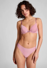 Roze beha en bijpassende slip van gladde stof. De beha heeft een diep decolleté en verstelbare bandjes. De slip heeft een normale taille en een naadloos ontwerp.