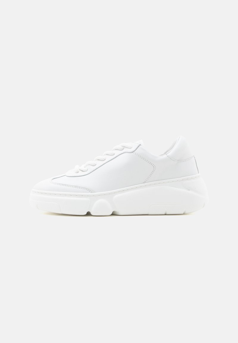 Λευκό χαμηλό sneaker με παχιά σόλα, μπροστινό δέσιμο με κορδόνια και μαλακό δερμάτινο επάνω μέρος, εμφανίζεται σε πλάγια όψη σε λευκό φόντο.