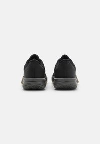 Czarne buty sportowe z fakturowaną cholewką, wyściełanym kołnierzem i gumową podeszwą. Cechy obejmują gładkie wykończenie oraz kontrastujący akcent na pięcie.
