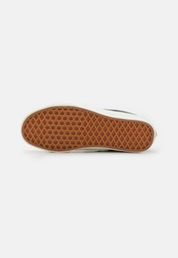 Rubber sneaker sole with a brown, textured grip pattern and white edges. Features a curved shape and flat, smooth surface for traction.