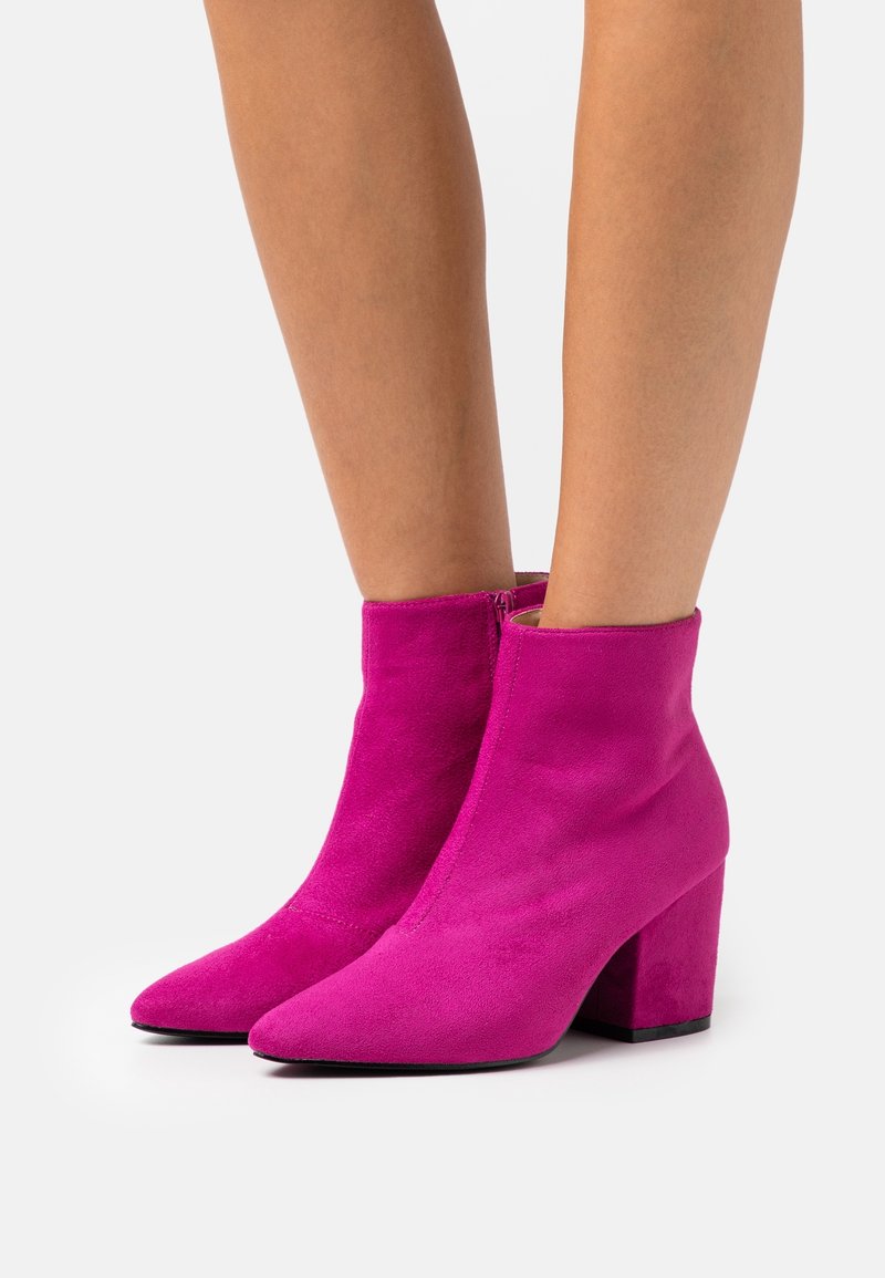 Bottines en daim fuchsia avec un bout pointu et un talon carré, dotées d'une fermeture éclair latérale et d'une texture lisse.