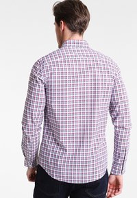 Kvit, röd och blå rutig skjorta med knappar. Har långa ärmar, krage i klassisk stil och en slim fit-design med en ryggsömn.