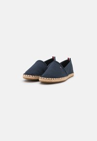 Espadrillas in tela blu marina con suola in juta intrecciata, caratterizzate da una punta appuntita e sottili accenti rossi e bianchi sul tallone.
