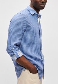 Μπλε πουκάμισο με ρίγες, λευκές κάθετες ρίγες, μακριά μανίκια σηκωμένα, ελαφρύ ύφασμα, χαλαρή εφαρμογή, λεπτομέρεια στο γιακά.