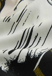 Tela ligera con un patrón abstracto en blanco y negro con rayas; textura suave; los pliegues resaltan los detalles del diseño sobre un fondo más claro.