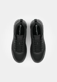 Black athletic shoes with mesh panels and lace-up design. Features a padded collar and textured rubber sole. Champion logo visible on the tongue.