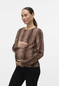 Majica dugih rukava s leopard uzorkom u smeđoj i crnoj boji, nosi se preko zaobljenog trbuha, u kombinaciji s crnim hlačama; glatka tekstura i opušten kroj.