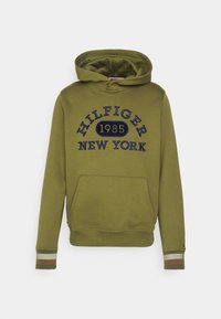 Sudadera verde oliva con un gran gráfico en azul marino que dice "HILFIGER NEW YORK 1985". Cuenta con un bolsillo frontal y puños de canalé a rayas.
