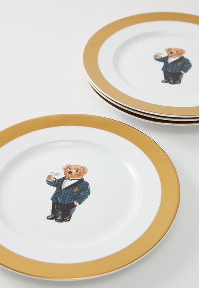 Okrogla porcelanska krožnik z zlatim robom, ki prikazuje barvito ilustracijo medveda v karirasti jakni, ki drži koktajl.