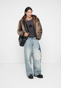Hanorac căptușit cu blană maronie peste un tricou gri închis cu o stea neagră. Purtați cu blugi lejeri bleumarin deschis cu accente albastre. Geantă neagră și saboți.