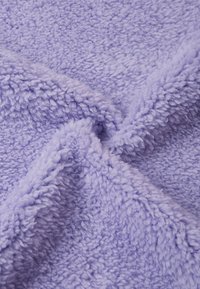 Coperta plush lavanda con una texture soffice, caratterizzata da un pelo spesso e morbido e da un aspetto stropicciato dovuto alla piegatura.