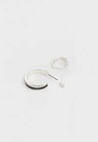 Boucles d'oreilles en argent avec des accents noirs et une petite boucle d'oreille à motif texturé. L'anneau présente un design courbé élégant et une finition brillante.