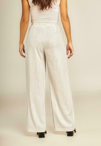 Witte wijde broek met verticale zilveren strepen, met een gladde textuur en een aansluitende hoge tailleband. De achterkant toont ruime draping.