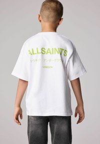 Baltas kokvilnas T-krekls ar oversized piegriezumu, ar lielu zaļu "ALLSAINTS" tekstu un papildus rakstzīmēm aizmugurē. Ikdienišķs dizains, īsām piedurknēm.