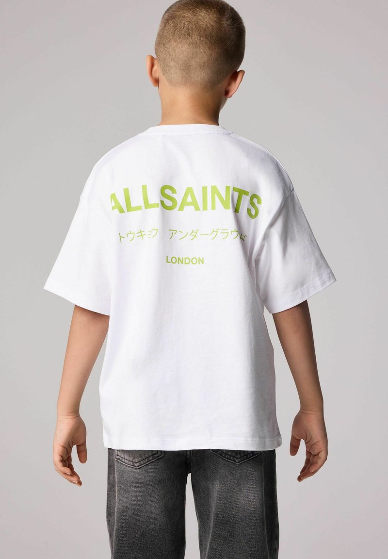 Baltas kokvilnas T-krekls ar oversized piegriezumu, ar lielu zaļu "ALLSAINTS" tekstu un papildus rakstzīmēm aizmugurē. Ikdienišķs dizains, īsām piedurknēm.