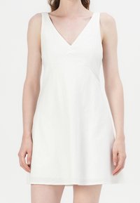 Weißes Leinenkleid mit V-Ausschnitt und ärmellosem Design. Hat eine ausgestellte Form und eine subtile Textur, geeignet für warmes Wetter.