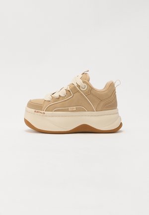 Beżowe sneakersy na platformie z grubą białą podeszwą, masywnymi białymi sznurówkami, zamszową fakturą oraz brandingiem "Buffalo" na boku i na przodzie podeszwy.