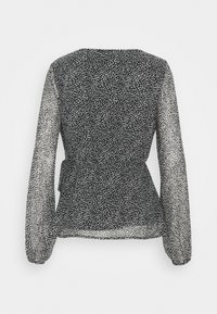 Blusa nera trasparente con motivo a pois bianchi irregolari, maniche lunghe a sbuffo, vita affusolata e orlo leggermente svasato, vista da dietro.