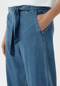 Blauwe denim broek met een losse fit, voorzien van een gestrikt middel, zijzakken en een zachte textuur.