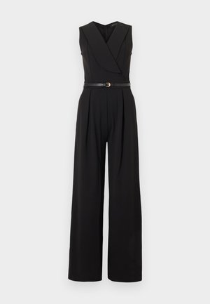 Combinaison noire sans manches à jambes larges, col en V croisé et ceinture fine noire avec boucle dorée à la taille.