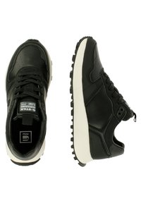 Czarne sneakersy z gładką skórzaną cholewką, białą, grubą gumową podeszwą oraz wyściełanym kołnierzem. Charakteryzują się perforowanymi detalami i metką z logo.