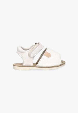 Sandalia de cuero blanco con tira de velcro, parte trasera abierta y punta redonda. Presenta un acento de cuero beige y parte superior texturizada, suela plana.