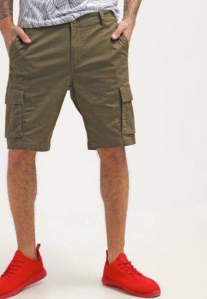 Pantaloni cargo verde oliva con due tasche laterali. Realizzati in tessuto resistente, presentano una vestibilità comoda e passanti per cintura. Abbinati a sneakers rosse.