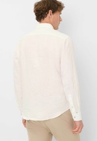 Lichtbeige langärmlig shirt van linnen, uitgerust met een klassieke kraag, enkele zoom en knoopmanchetten, met een structuurstofafwerking.